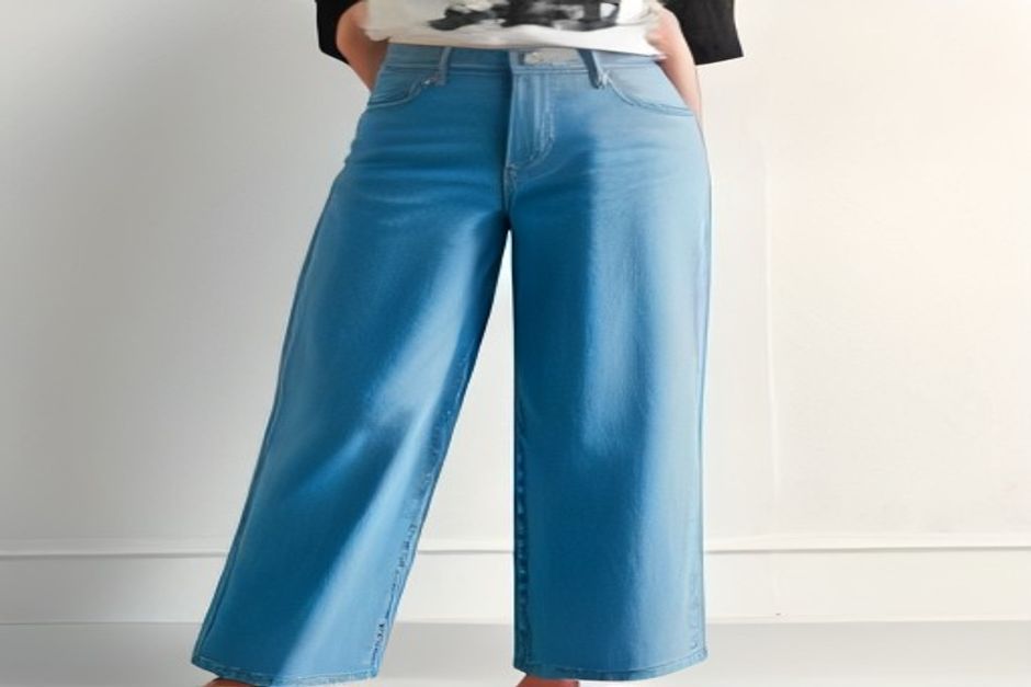 Wide leg jeans laid flat on a white surface, showing the hem flaring wider than the knee